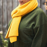 Person wearing a yellow scarf and green sweater outdoors