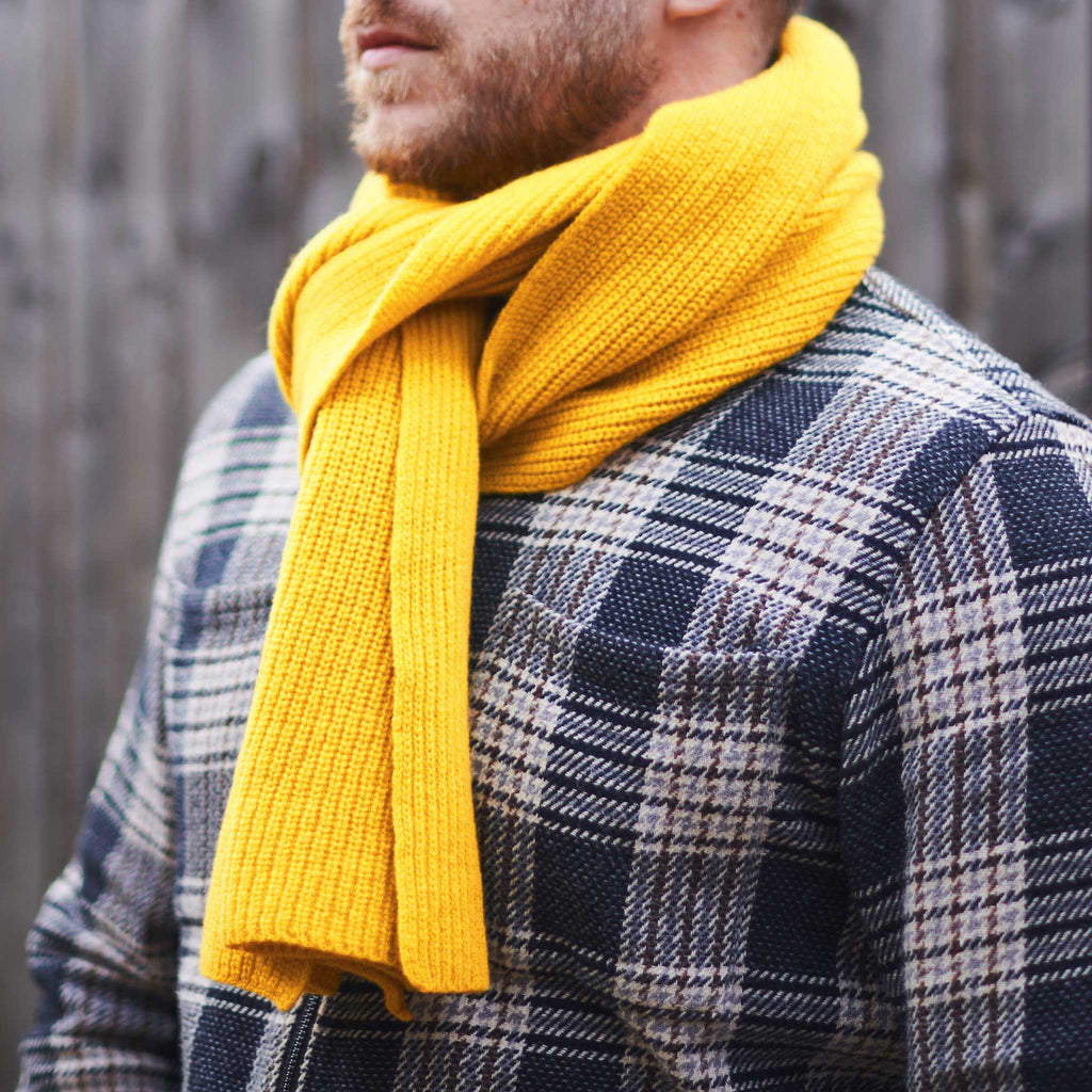 Person wearing a yellow scarf and plaid jacket against a blurred background