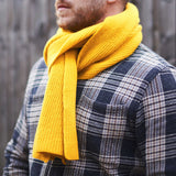 Person wearing a yellow scarf and plaid jacket against a blurred background
