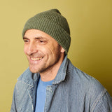 Man wearing a green beanie and striped jacket against a yellow background