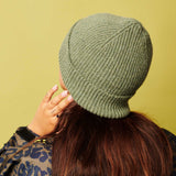 Person wearing a green knit beanie against a yellow background