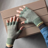 Green fingerless gloves being worn on a wooden surface