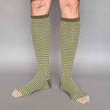Green and beige striped knee-high socks on a gray background