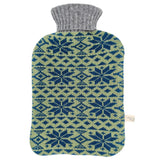A knitted hot water bottle cover with a gray ribbed neck and a blue and sage green Nordic snowflake pattern, shown on a plain white background.