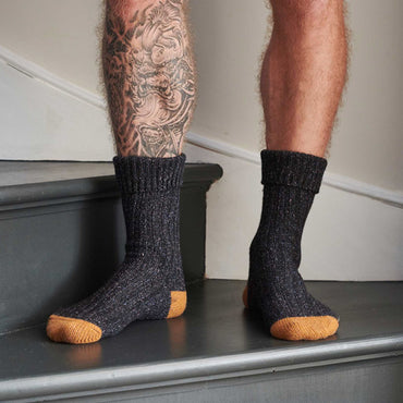 Person wearing dark gray socks with orange toes on a step.